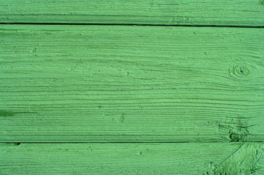 Structure of a fragment of a wall from boards painted with a green paint.