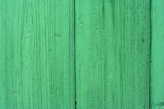 Structure of a fragment of a wall from boards painted with a green paint.