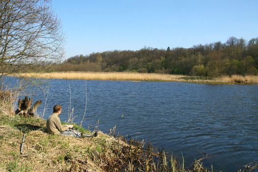 Fisherman sitting on the river shore