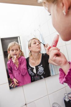 Mother and Daughter put on make-up in the bathroom