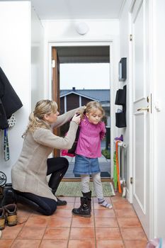 Mother helping her daughter with the jacket