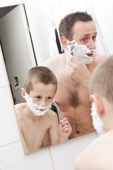 Happy Mature Man shaving in bathroom with his son