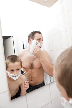 Happy Mature Man shaving in bathroom with his son