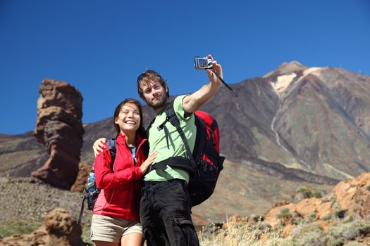 Couple taking picture having fun outdoors on vacation on Tenerife, Canary Islands. The volcano Teide and the famous Garcia Rock in the background. Young beautiful couple.