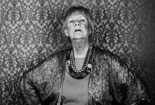 Portrait of snooty senior woman in front of gold background
