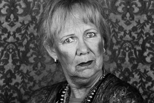 Portrait of skeptical senior woman in front of gold background