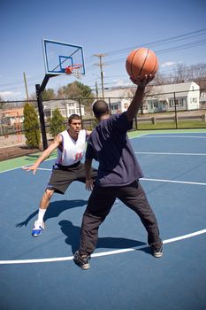 A young basketball player is taunting his opponent with the ball while playing one on one.