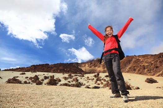 Happy hiking with arms in the air. Woman hiker excited and cheerful travelling on Teide, Tenerife, Canary Islands.