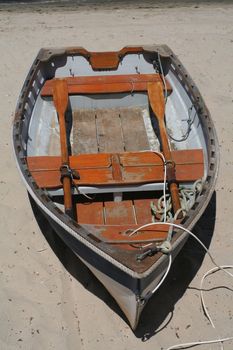 An old row boat on a white sand beach