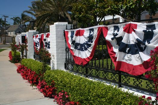 Red, White, and Blue banners hang on a black iron fence.