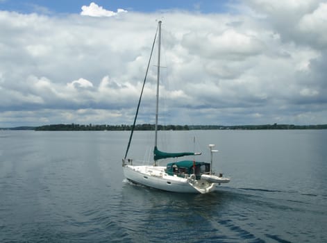 Quiet white small boat floating on the lake of Ontario, Canada, between the thousand islands by cloudy weather