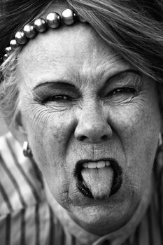 Closeup of rude old woman sticking out her tongue