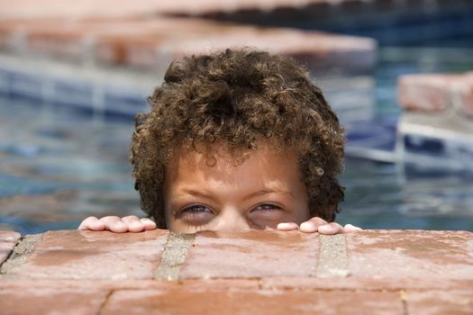 Cute young boy with green eyes in a swimming pool