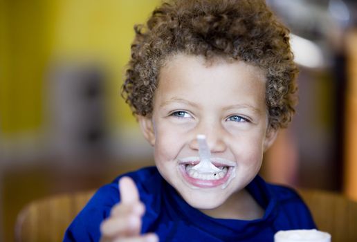 Handsome young boy with blue eyes eating yogurt