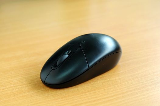 A black computer wireless mouse on a desk