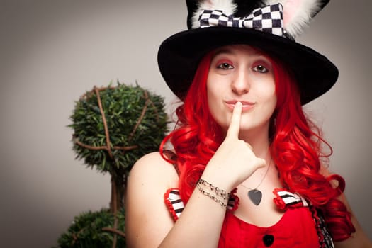 Attractive Red Haired Woman Wearing Bunny Ear Hat on a Grey Background.