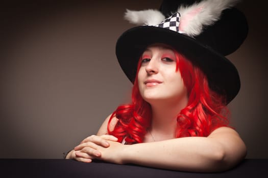 Attractive Red Haired Woman Wearing Bunny Ear Hat on a Grey Background.