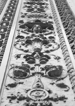 Black and white image of ornate design facade of building with female bust