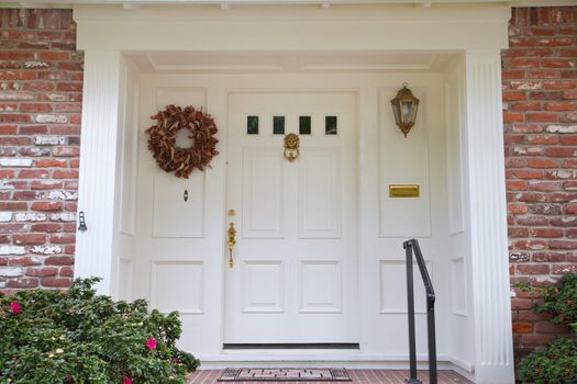 White colonial style door with brass fittings on a brick house