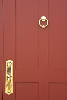 Burgundy coloured door with brass handle and knocker