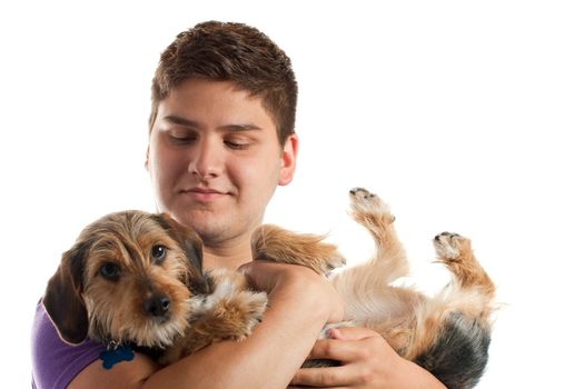 High key portrait of a young man holding a cute mixed breed dog isolated over white. Shallow depth of field with focus on the mans face.