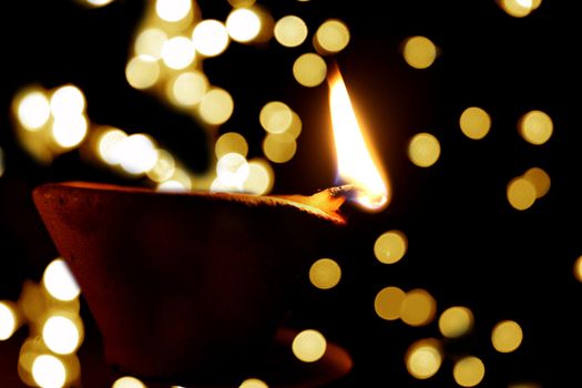 A traditional Diwali lamp lit on the backdrop of many other blur diwali lamps.