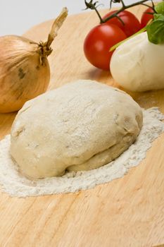 yeast dough, cheese, tomatoes and an onion on a wooden board