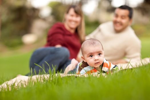 Happy Crawling Baby Boy and Mixed Race Parents Playing in the Park.