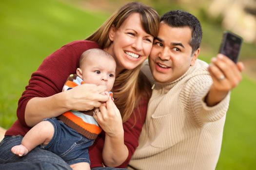 Happy Mixed Race Parents and Baby Boy Taking Self Portraits at the Park.