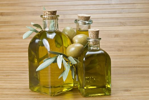 Olive oil bottles and olives on a bamboo mat.