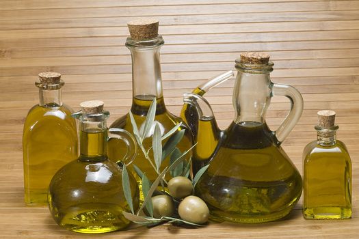 Olive oil bottles and olives on a bamboo mat.