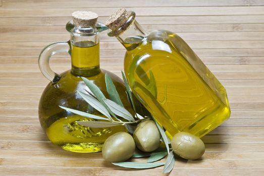 Olive oil bottles and olives on a bamboo mat.