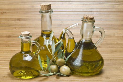 Olive oil bottles and olives on a bamboo mat.