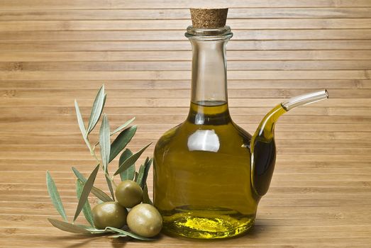 Olive oil bottles and olives on a bamboo mat.