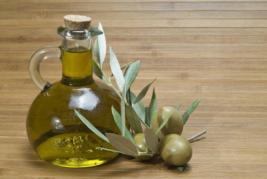 Olive oil bottles and olives on a bamboo mat.