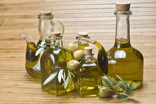 Olive oil bottles and olives on a bamboo mat.