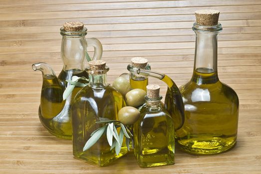 Olive oil bottles and olives on a bamboo mat.