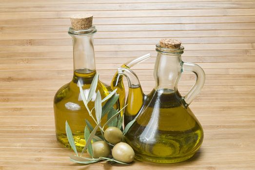 Olive oil bottles and olives on a bamboo mat.