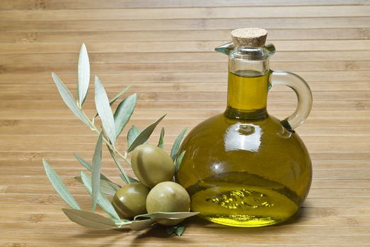 Olive oil bottles and olives on a bamboo mat.