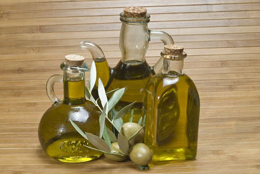 Olive oil bottles and olives on a bamboo mat.