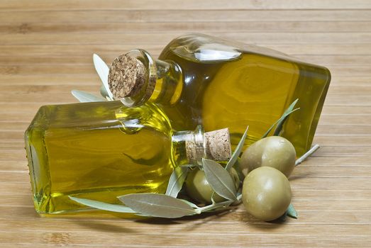 Olive oil bottles and olives on a bamboo mat.