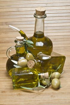 Olive oil bottles and olives on a bamboo mat.