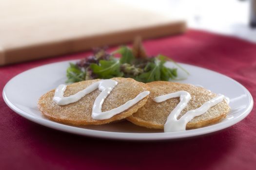 Potato pancake snack with sour cream and salad.