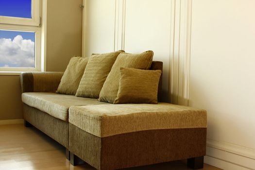 Angle shot of brown  sofa in living room with nice blue sky background in window.