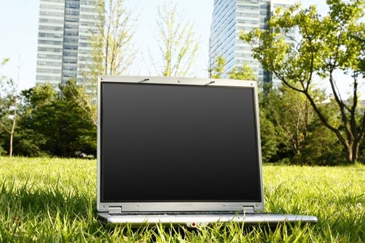 laptop in the grass with building background