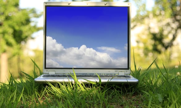 Laptop on green grass on a sunny day.
