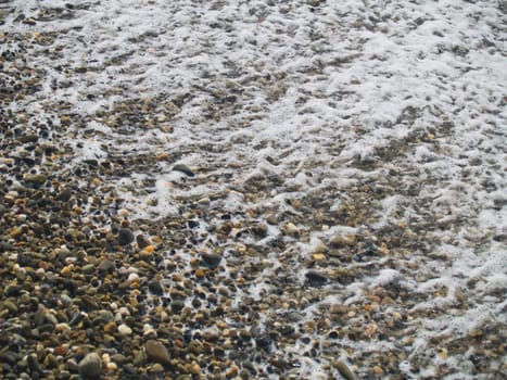 Wave foam on a pebbles, close-up