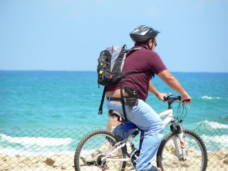 White middle age man with hard hat and gun on bicycle