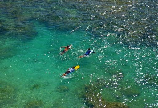 Surfers paddling out to the Indian Ocean from Uluwatu beach, Bali, Indonesia.