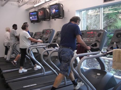 A few people are exercising on the treadmills at a health club.